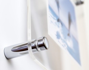 Close-up of chrome standoff hardware holding a clear acrylic panel on a wall.