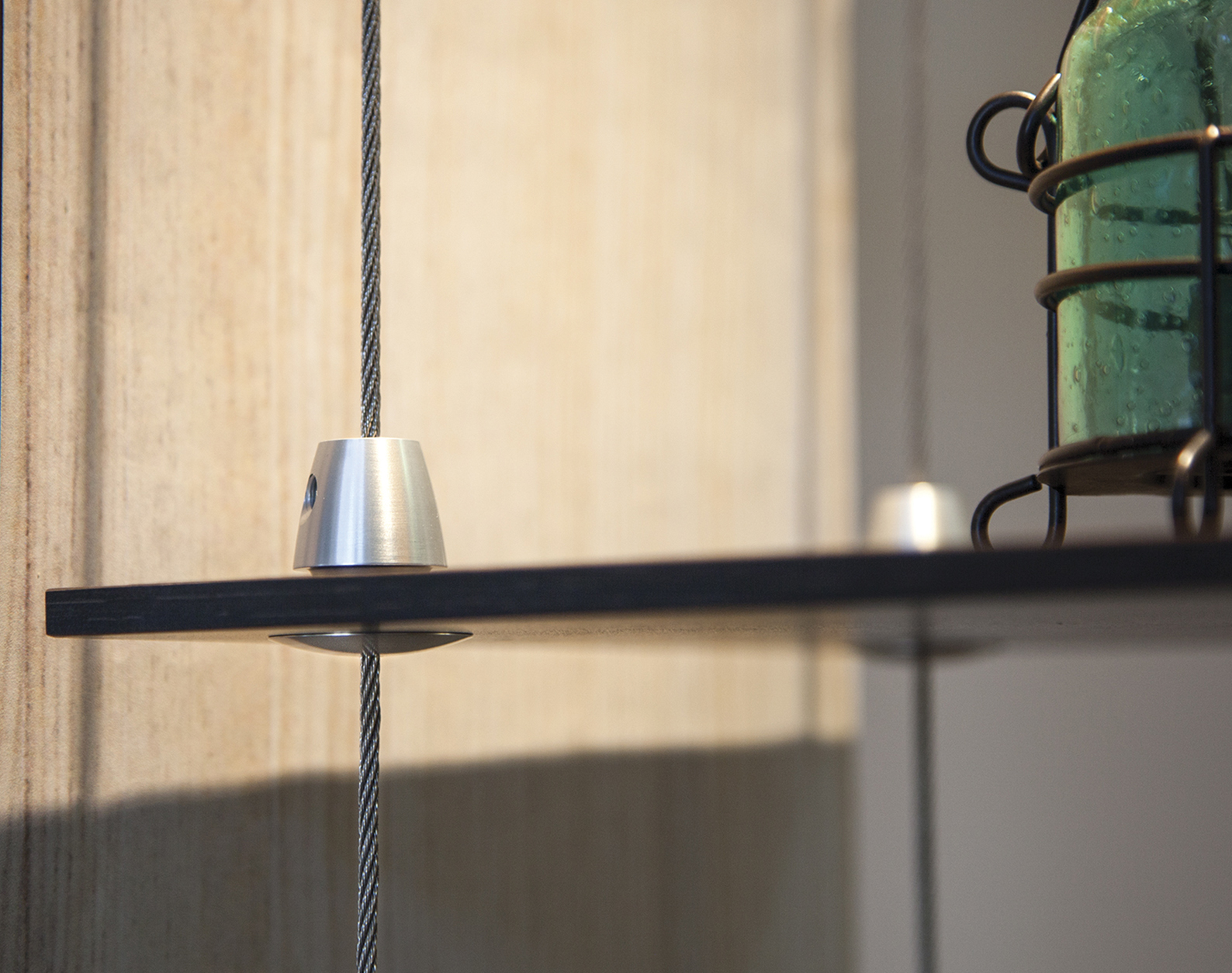 Close-up of a glass shelf secured with a wire display system and metal shelf support hardware.