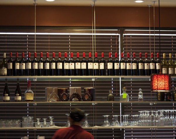 Wine bottles displayed on glass shelves suspended with a wire display system.