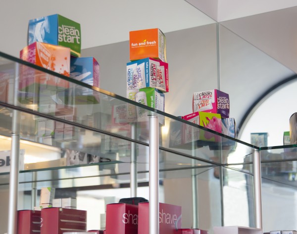 Glass retail shelves supported by aluminum rods and mounting hardware displaying boxed products.