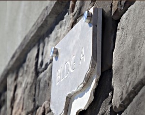 Stone plaque mounted on an outdoor rock wall with stainless steel standoffs.