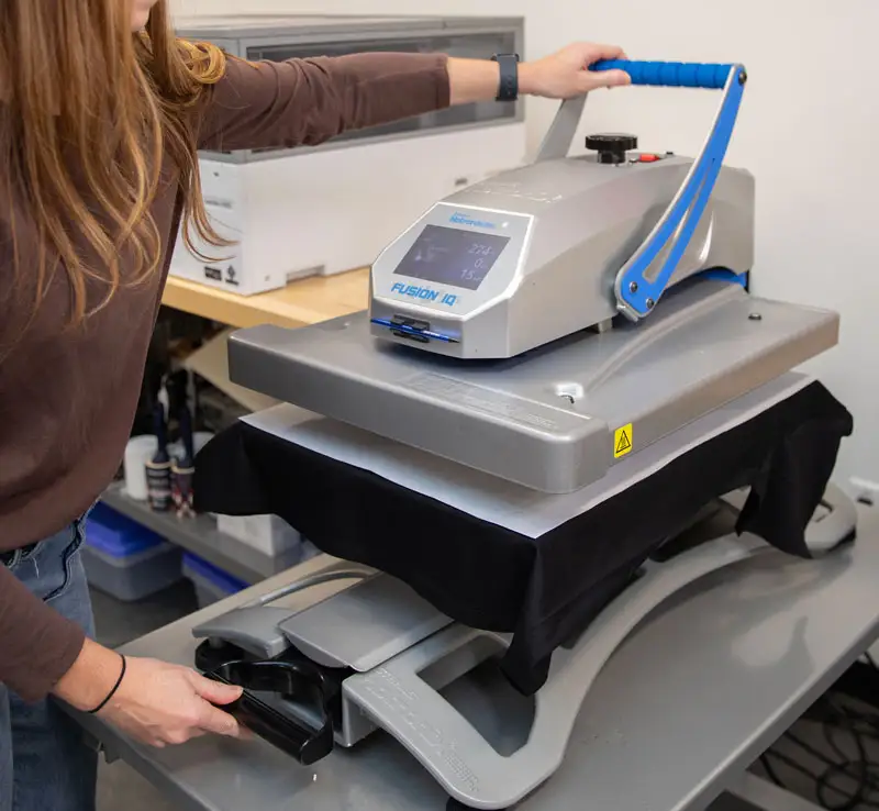 Woman pressing a black t-shirt with a Fusion IQ heat press