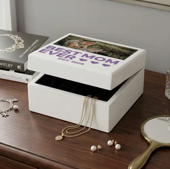 white jewelry box sitting on a dresser with jewelry beside it and coming out of it with a picture of a mom and baby on it that says best mom ever in purple