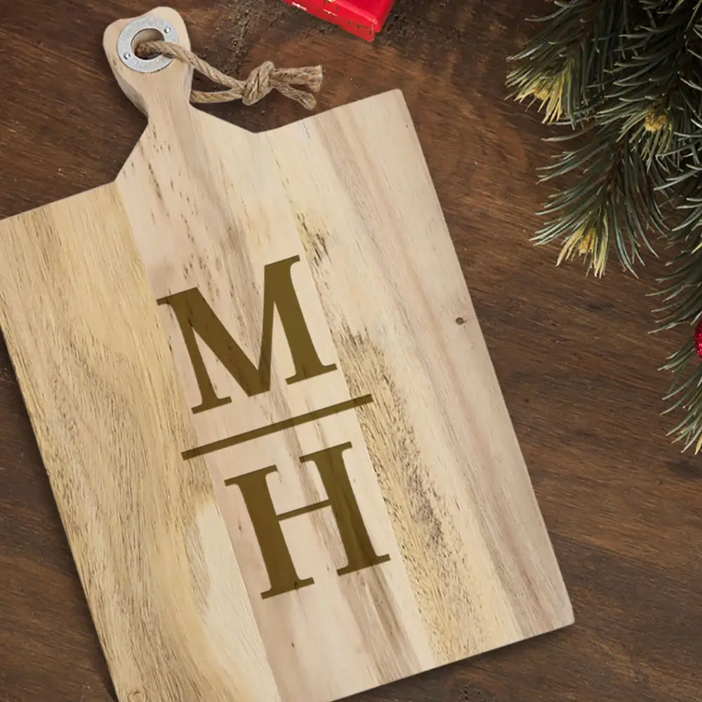 image of an engraved acacia cutting board sitting on a table with christmas greenery.