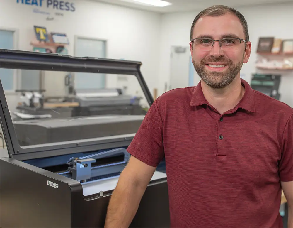 JPPlus Team Member Standing with a Flux Laser Engraver