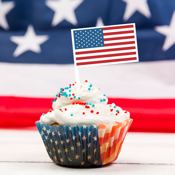 LaserMax Tri-layer sheet engraved and cut to an American flag cupcake topper sitting in a cupcake with a flag in the background
