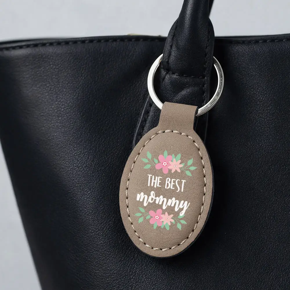 saddle buckskin keyring hanging on a black purse with print that says the best mommy and flowers