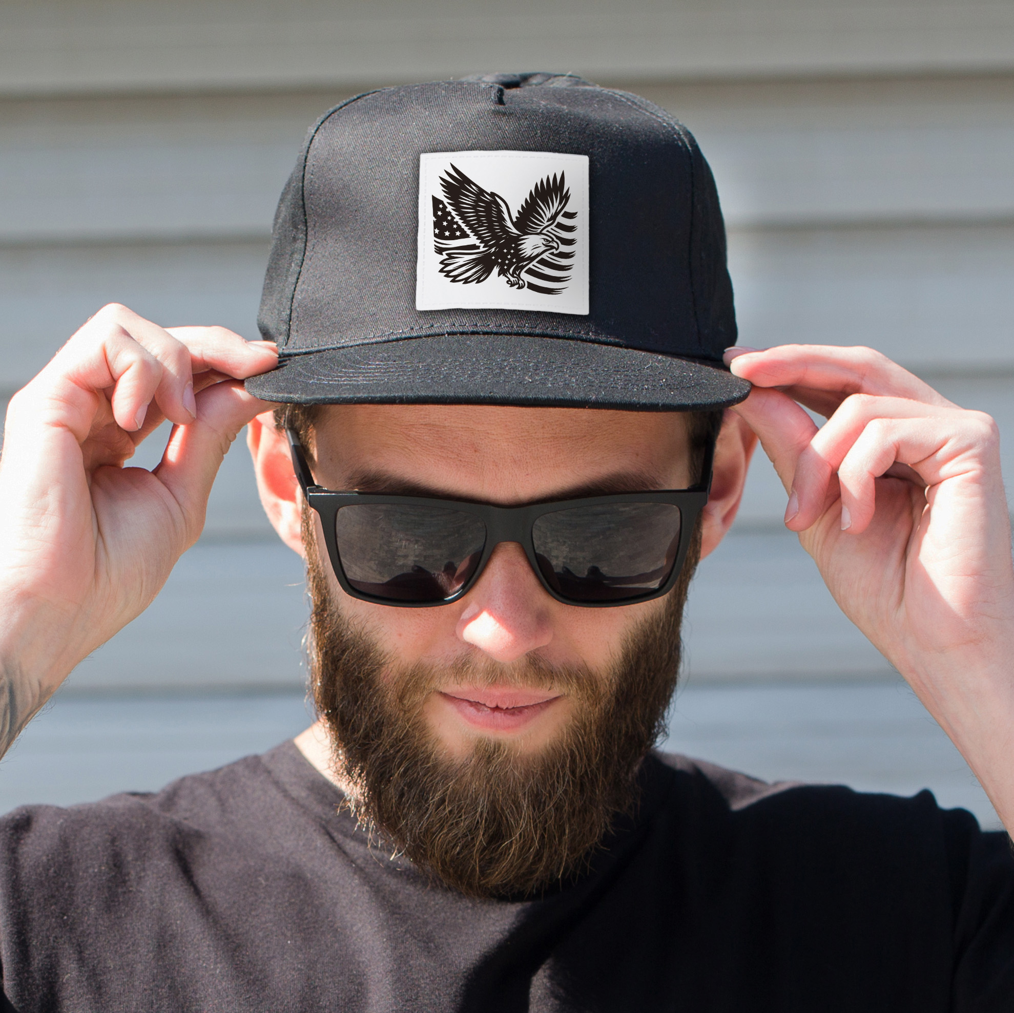saddle leather-like white hat patch engraved with eagle and American flag on a black hat. man wearing the hat standing outside