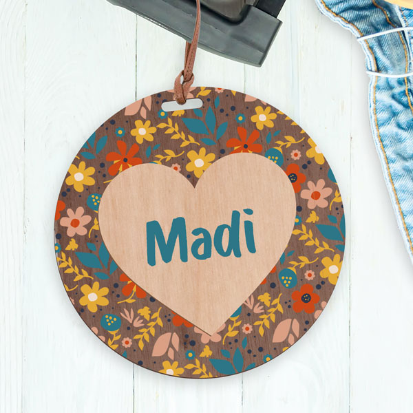 UV printed bag tag with floral pattern printed on a wood circle and the name Madi printed on a laser cut out wood heart