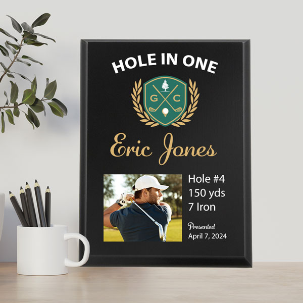 Black UV printed plaque with a hole in one award for Eric Jones featuring a picture of Eric golfing and his hole in one information. Plaque sitting on a desk