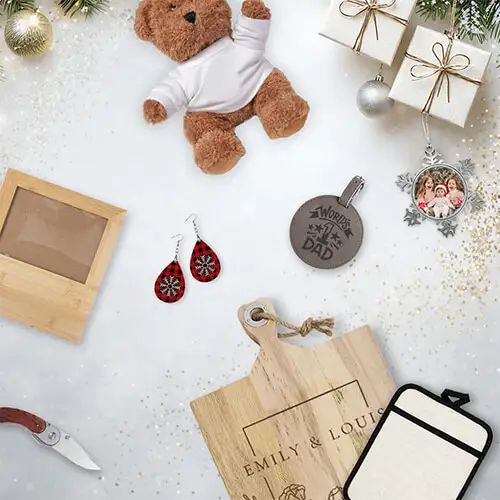 Holiday gifts on a white background, including a teddy bear, engraved cutting board, earrings, photo ornament, wooden frame, leather tag, and tumbler sleeve with festive decorations.