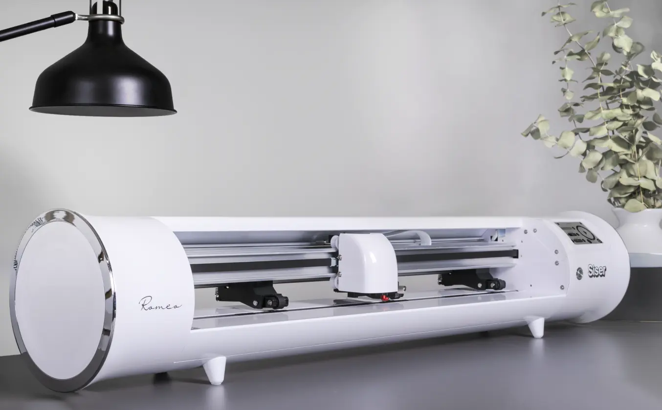 image of the Siser Romeo vinyl cutter sitting on a desk next to a plant and lamp