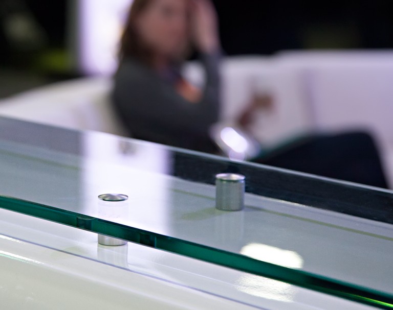 Close-up of glass countertop raised with metal standoff supports.